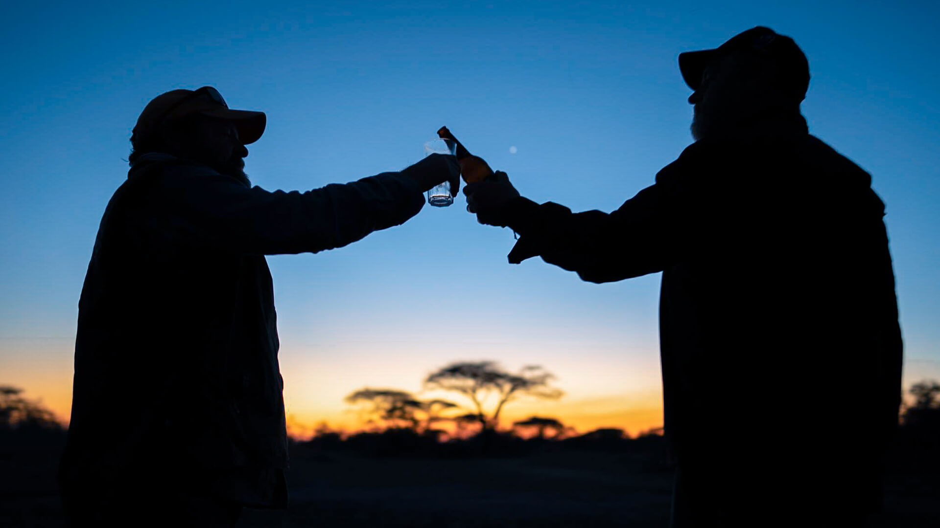 Guests clink glasses as night falls before they head out on a night game drive