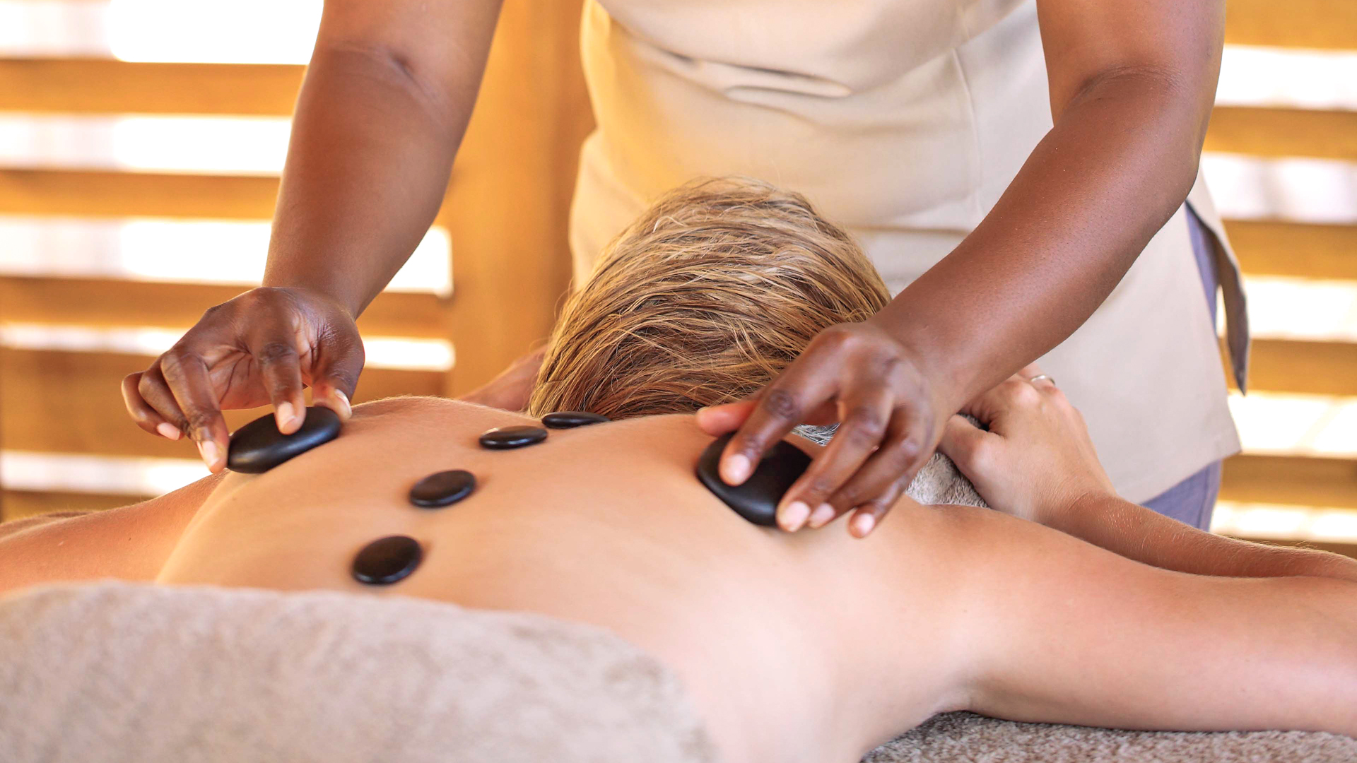 a guest receives a relaxing hot stone massage at jabali ridge - spa on safari - asilia africa