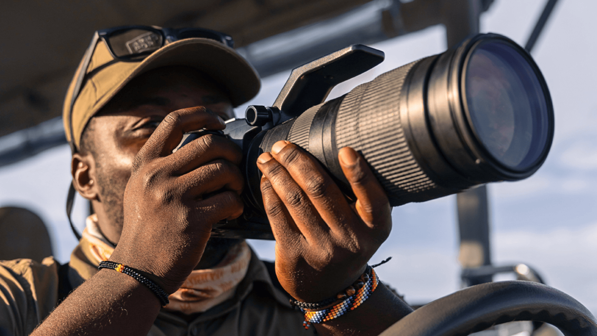 a safari guide looks through his camera on a safari vehicle - namiri plains - tanzania - asilia africa