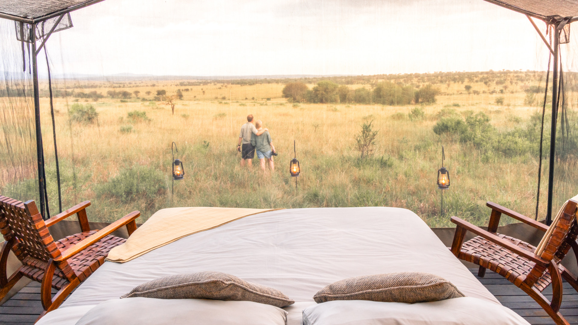 Serengeti National Park, lanterns outside star gazing tent with couple in the distance
