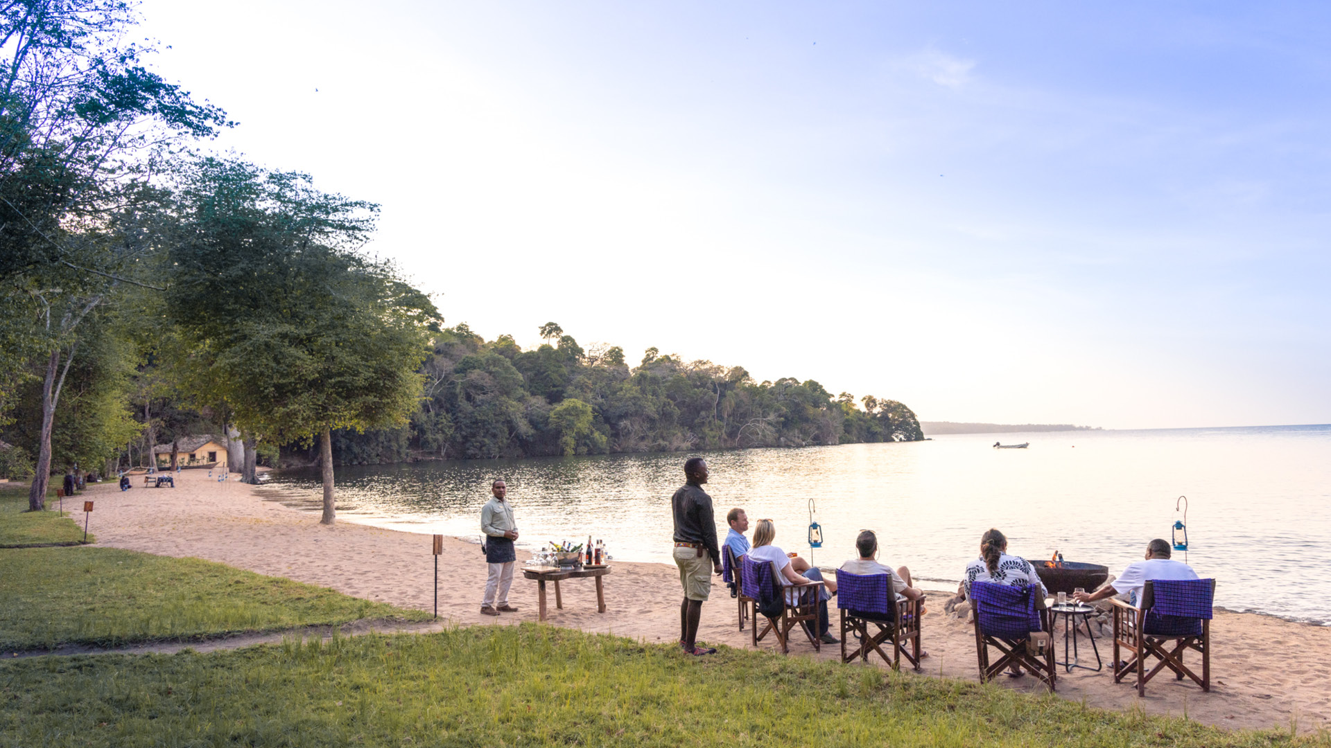 Lake Victoria, shore, guests by the fire with guide and waiter, drinks, chairs, sand