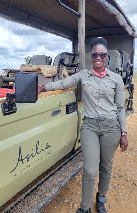 Grace, smiling alongside an Asilia Land Cruiser, Tanzania