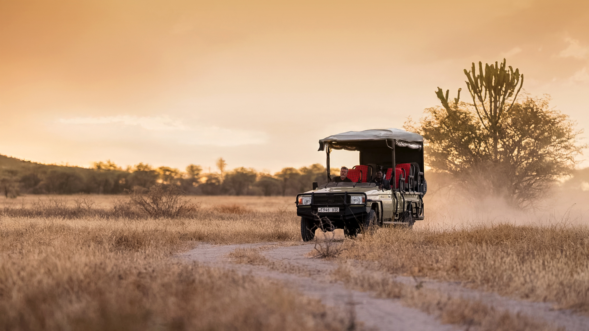 an asilia africa safari vehicle driving along the dusty track at dusk in southern tanzania