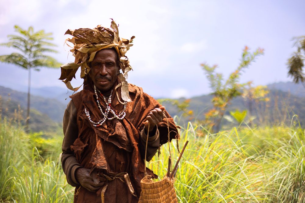 A Batwa man in tradition clothing with a woven basket, Bwindi, Uganda.