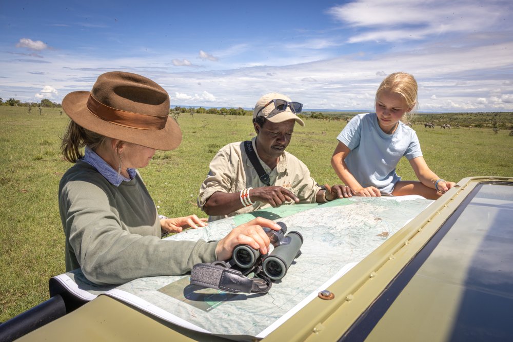 A mother and daughter examine a map with their guide in the Mara Naboisho Conservancy, Kenya.