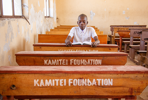 a child sits at his school desk supported by kamitei foundation tanzania