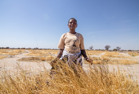 a female lead farmer stands in the grasslands outside Ruaha National Park
