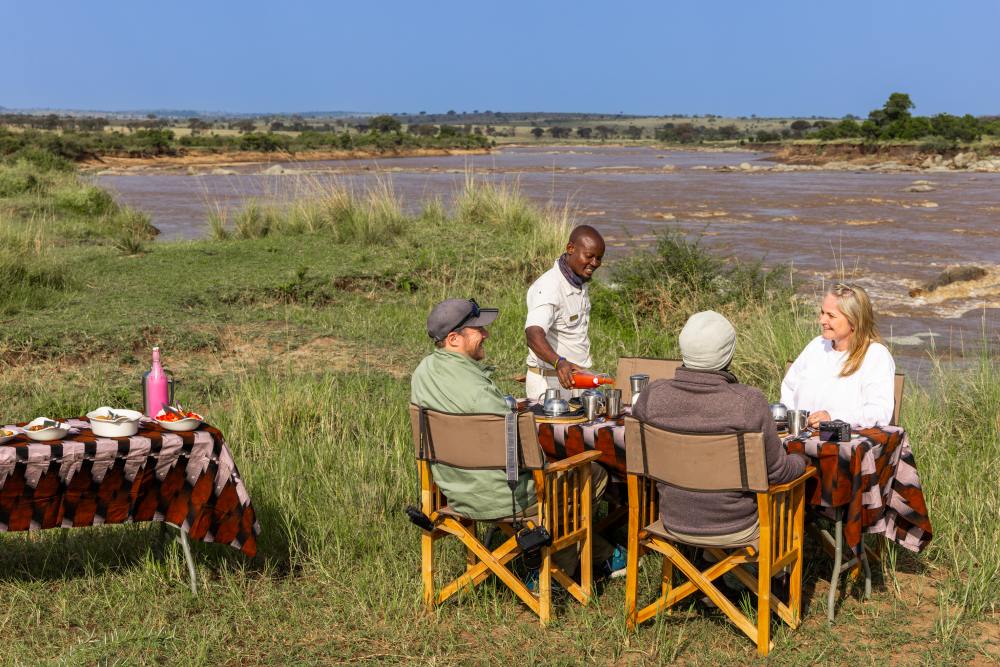 Guests enjoying a cooked breakfast alongside the Mara River, Tanzania.