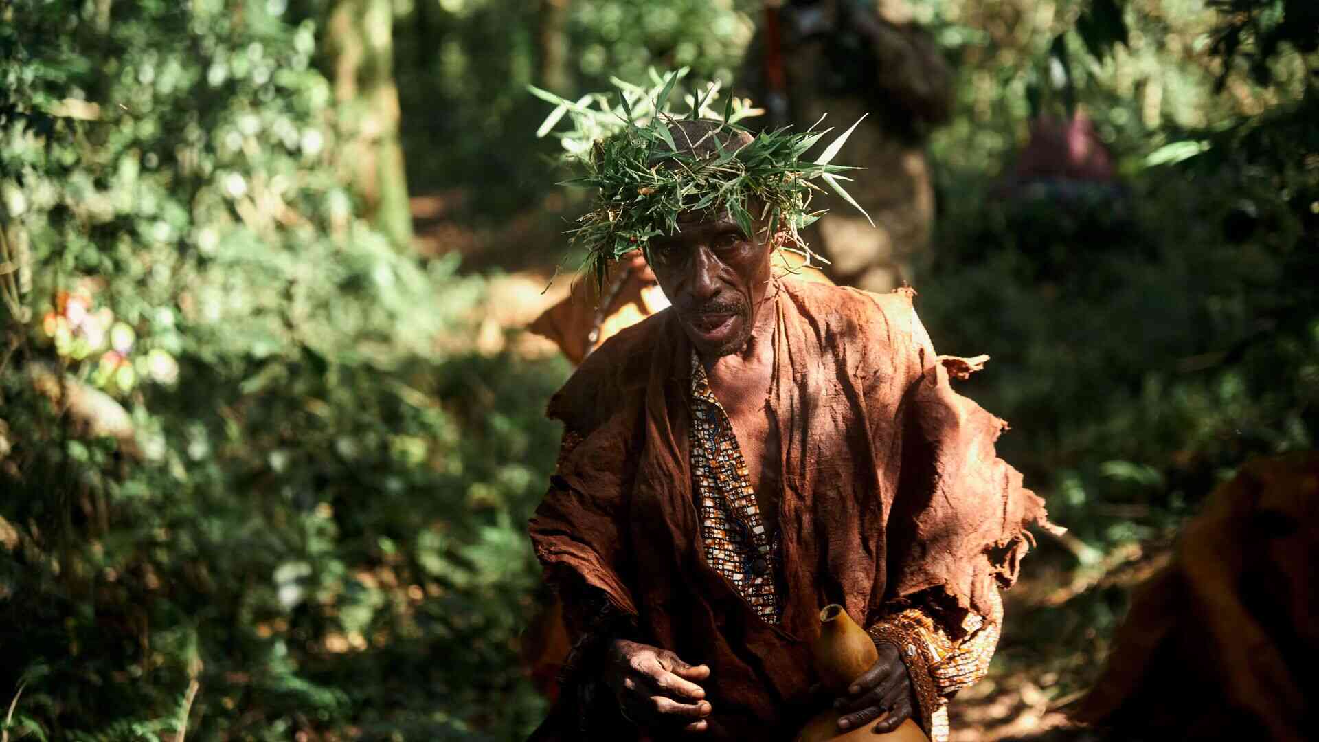 A tribesman of the Batwa community walk through the dappled light of Bwindi's forest